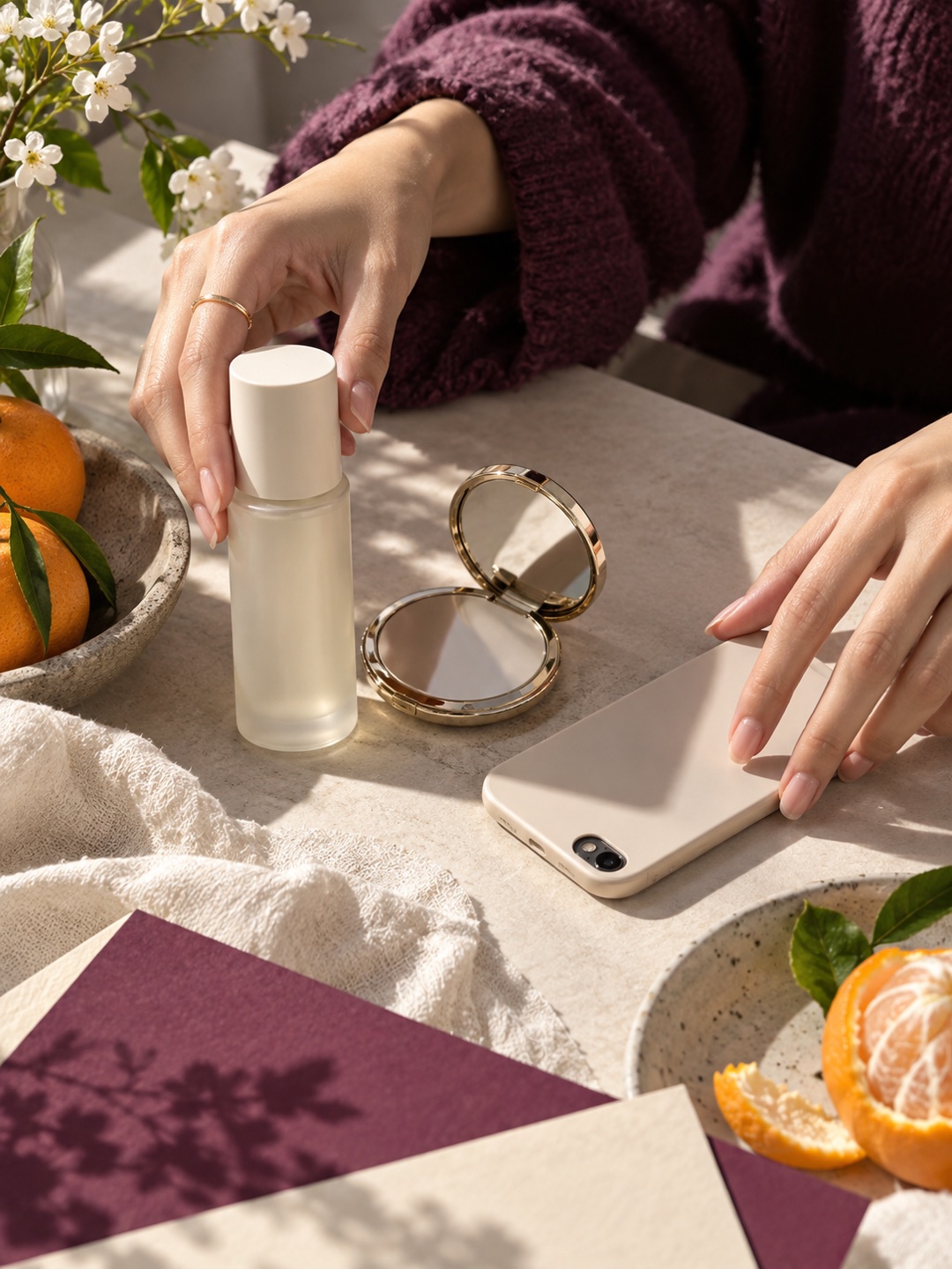 Hands arranging an unbranded skincare bottle beside a compact mirror and phone.